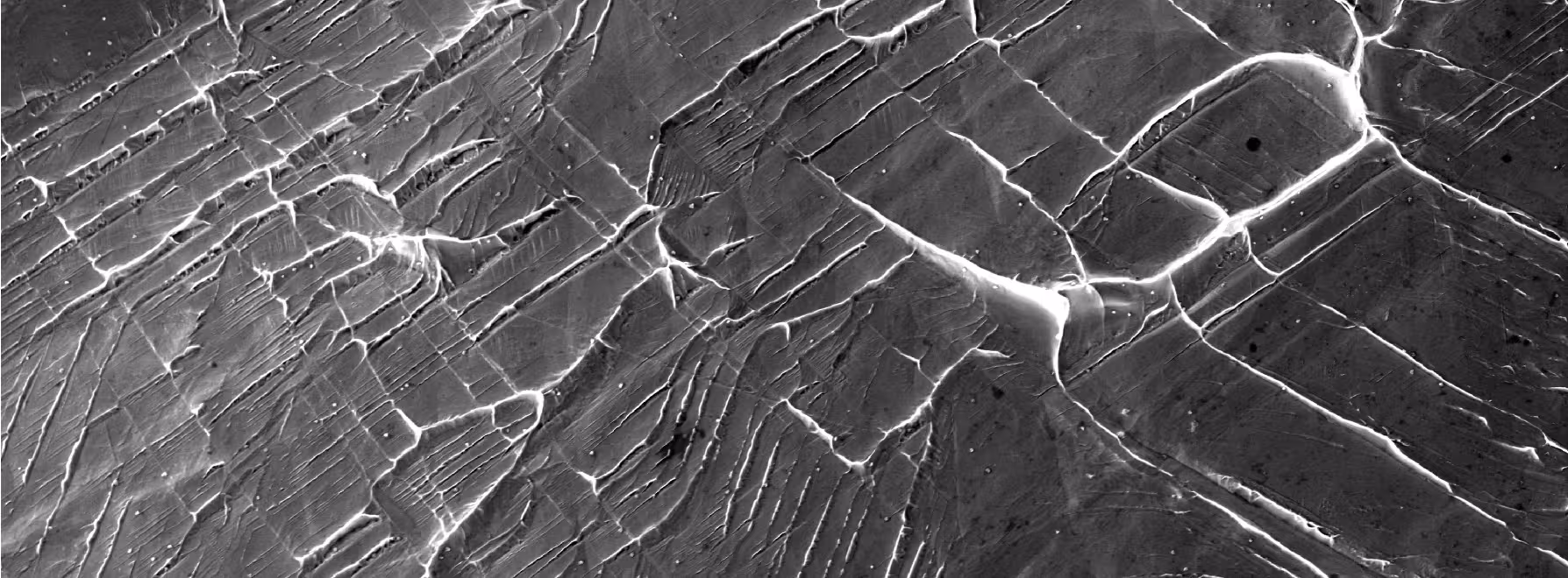 Electron microscopy image showing new defects forming between neighbouring crystals of the niobium-titanium-based alloys.